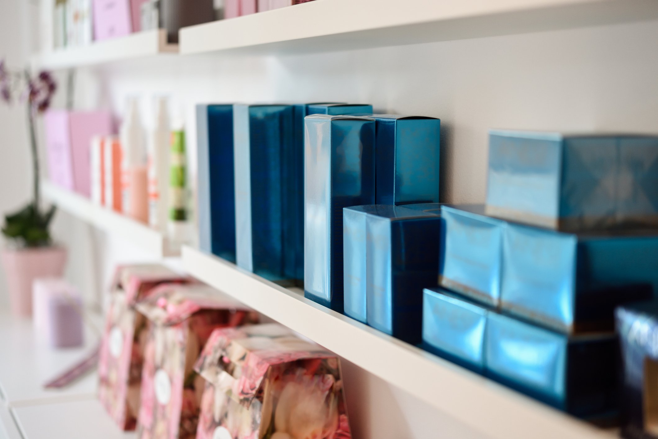 Boxes of luxury perfumes and skincare products line the shelves of a shop.
