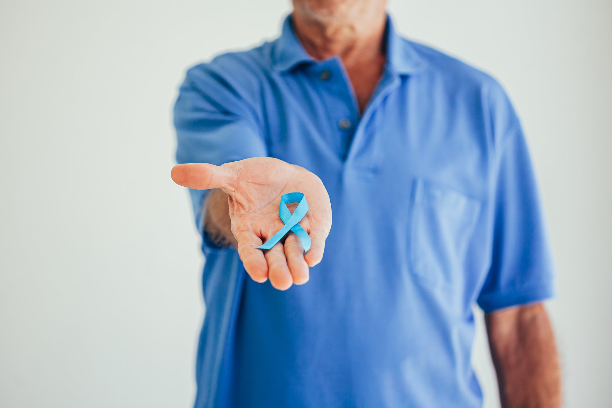 A man holding a prostate cancer ribbon in his palm.