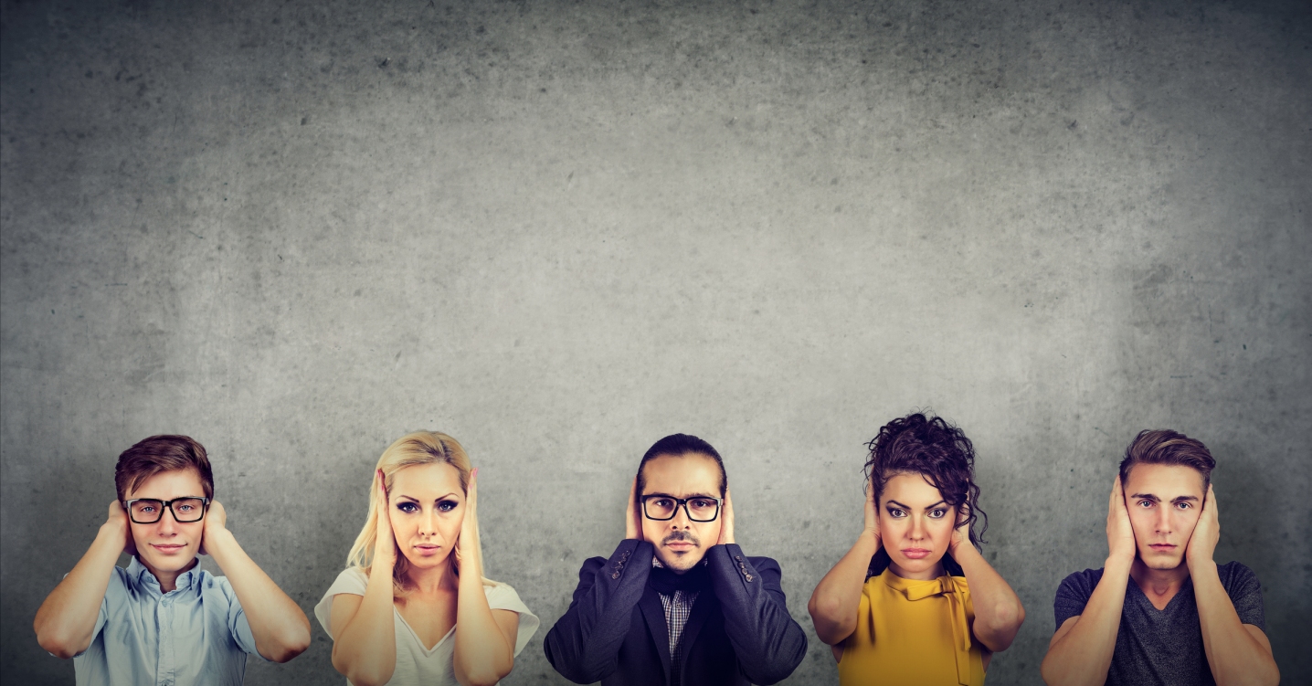 Five people lined up with their hands covering their ears