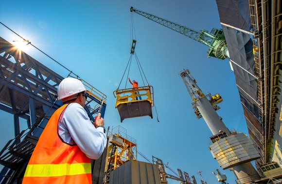 a construction worker looking up at a crane