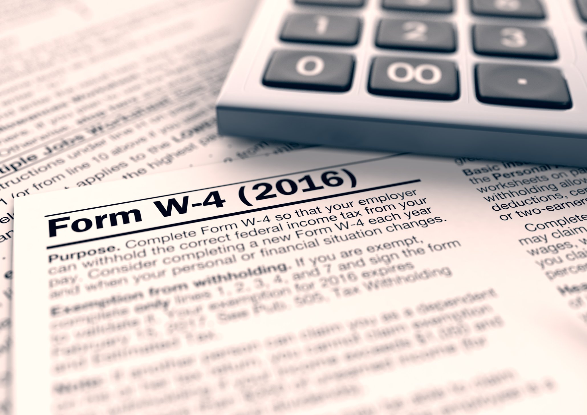 A W-4 tax form, next to a calculator. 