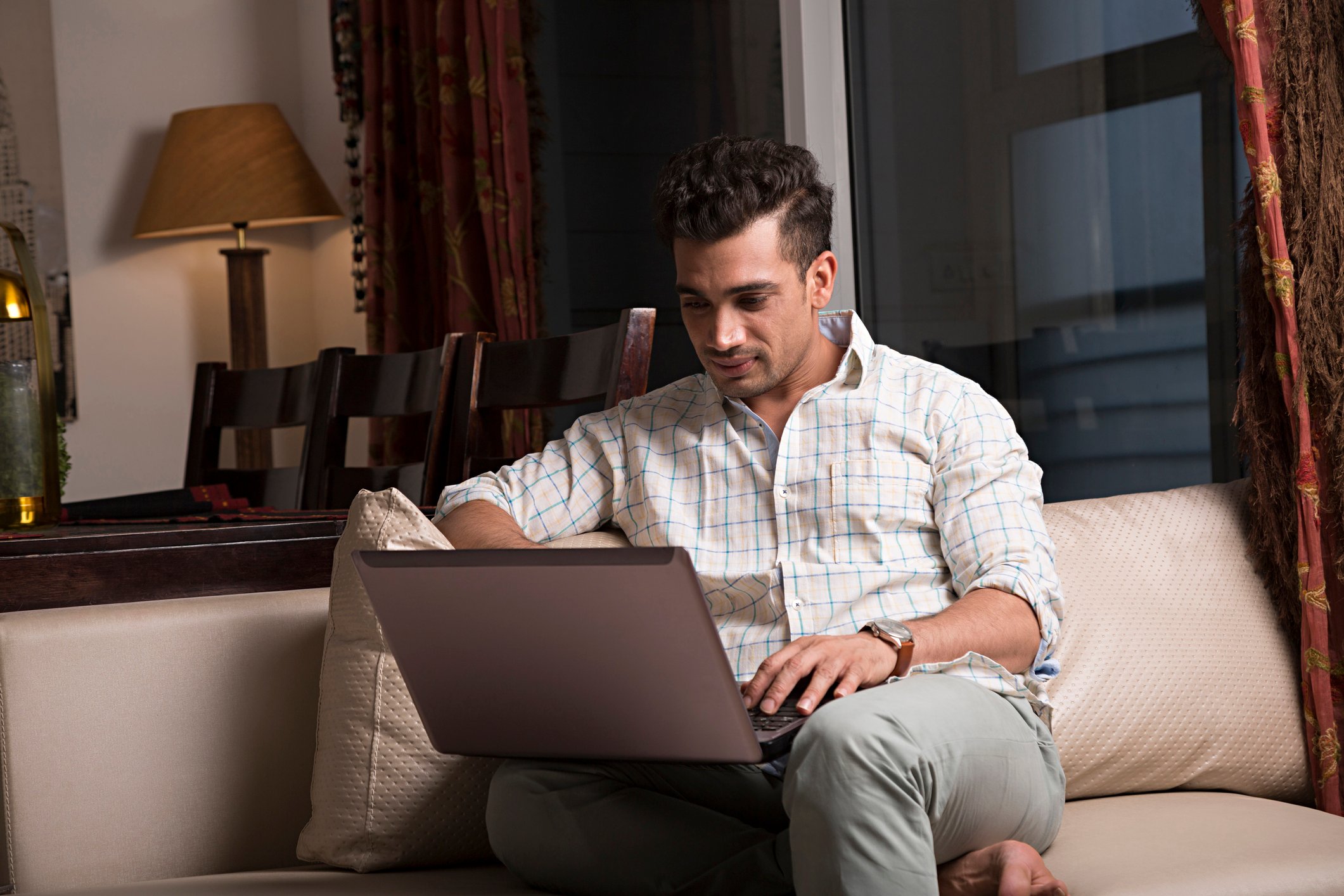 Young man on couch typing on laptop