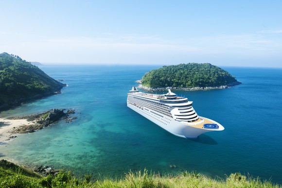 A cruise ship floating in a cove between two islands covered in greenery