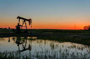 An oil pump next to a pond.