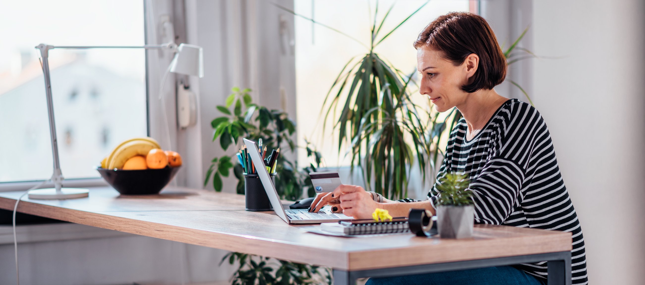 Woman holding credit card while using laptop.