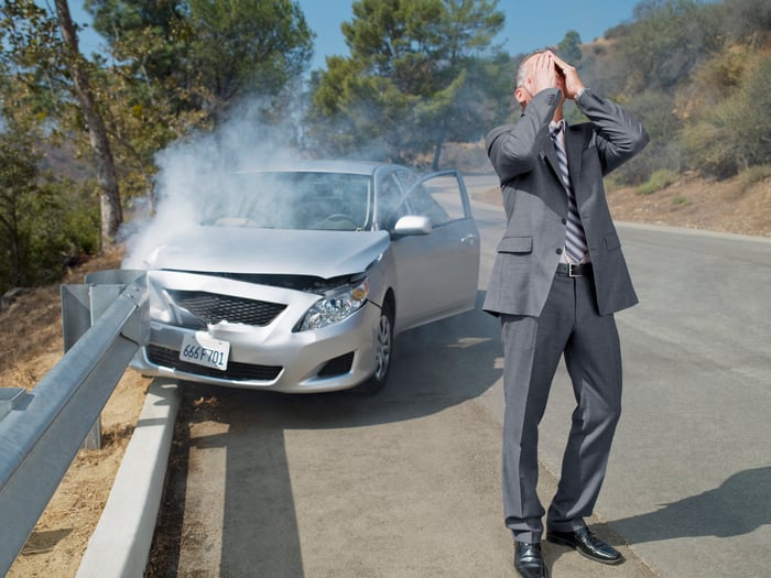 Frustrated man standing next to crashed car