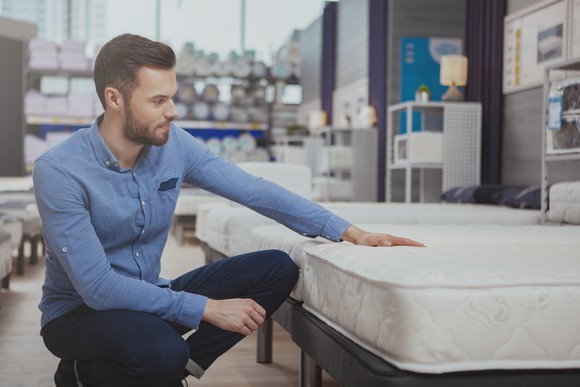A man inspects a sleep mattress in a store.