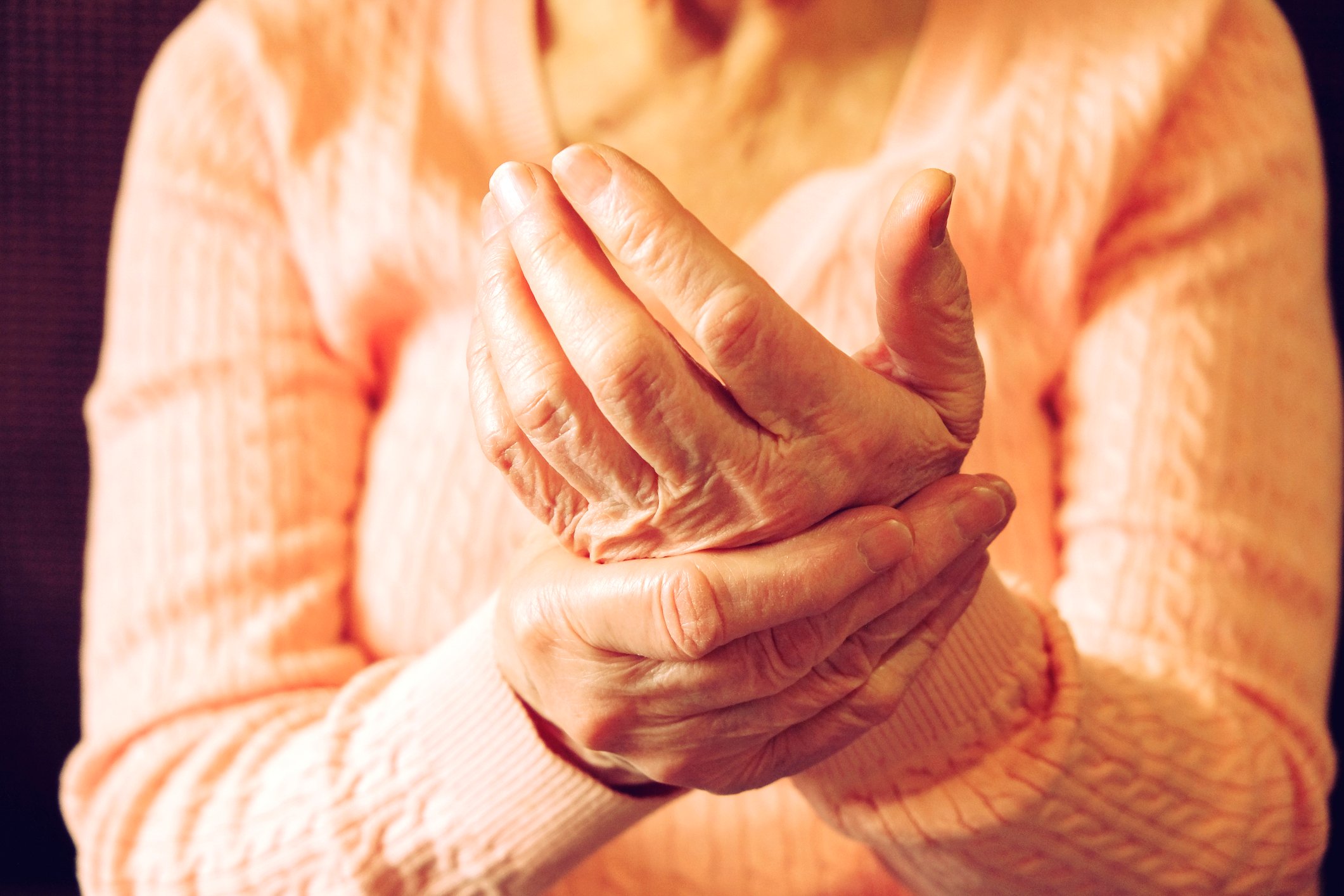 Elderly woman rubbing arthritic hand.