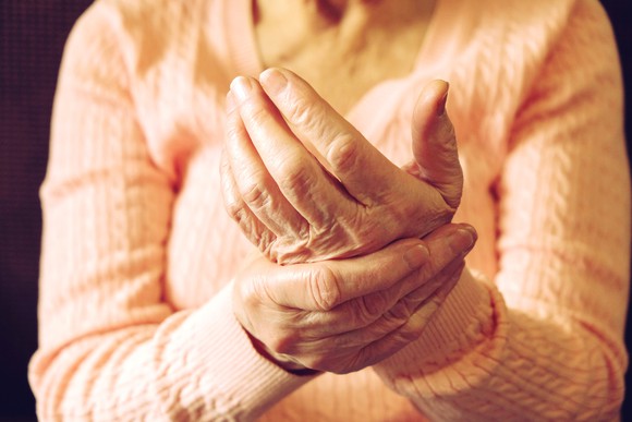 Elderly woman rubbing arthritic hand.