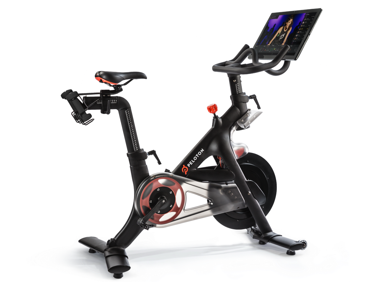 A Peloton stationary bike with a workout playing on the monitor.