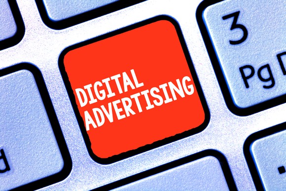 a portion of a computer keyboard is shown with the words "digital advertising" displayed on a red key.