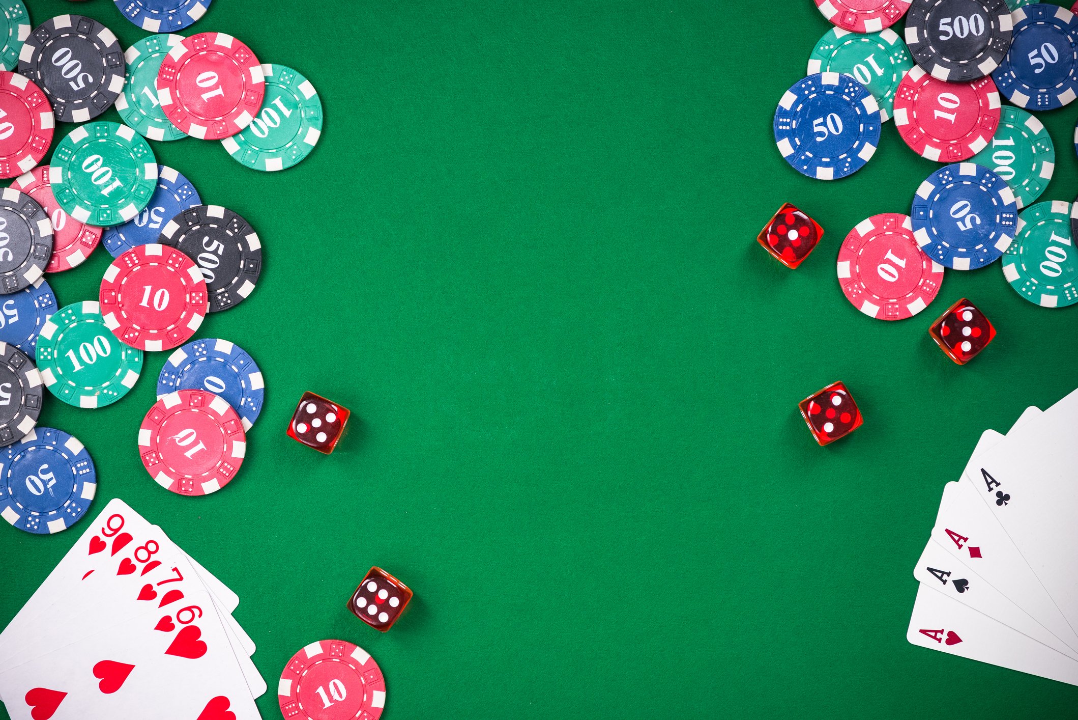 Casino table with red dice; red, blue, green, and black poker chips; a set of cards showing a straight flush, and another showing four aces. 