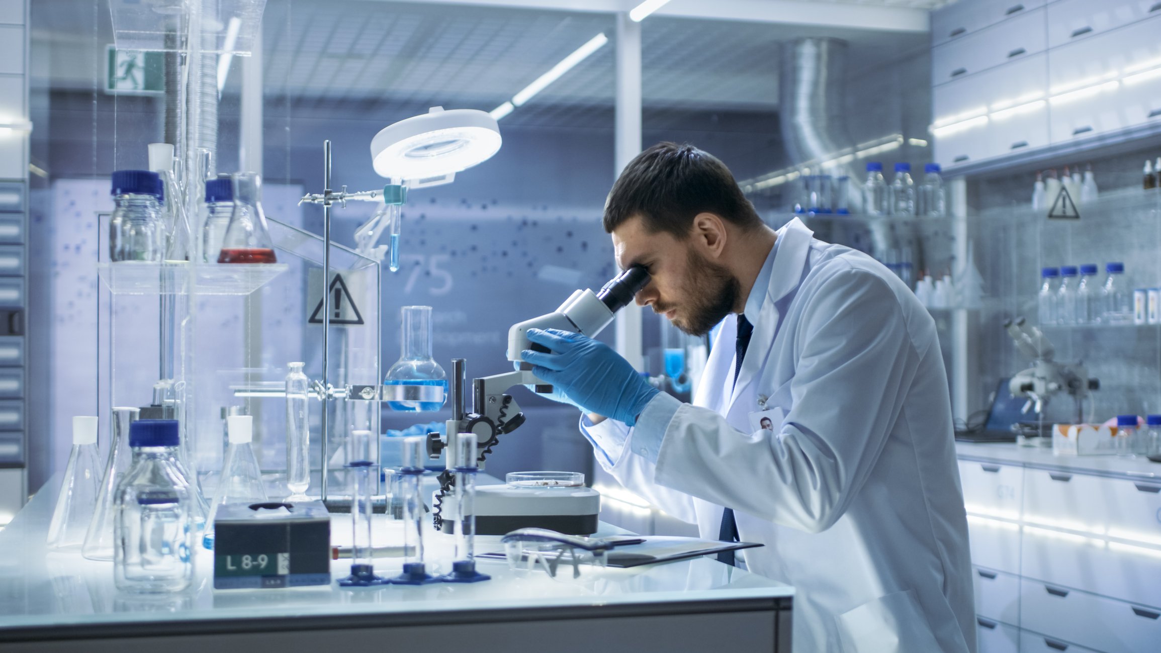 A scientist in a lab looking through a microscope.