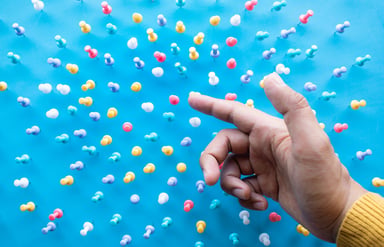 Finger pointing at pushpins on a blue field