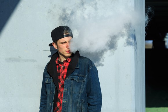 Young man exhaling vapor