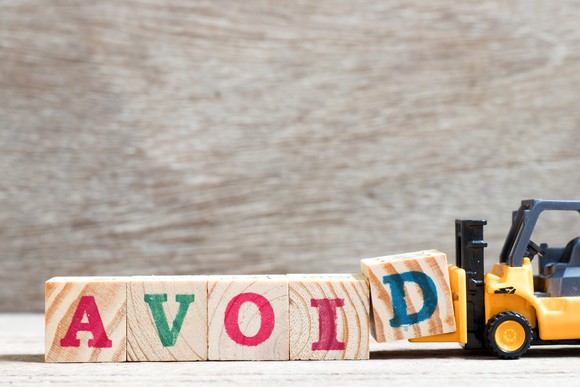 A toy forklift appearing to place wooden blocks in order that spell out the word avoid