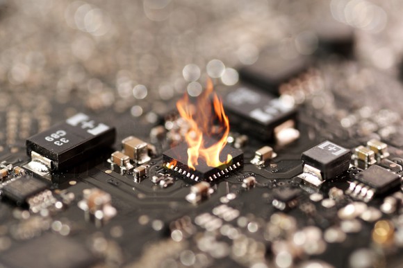 Close-up shot of a printed circuit board where one chip is on fire.