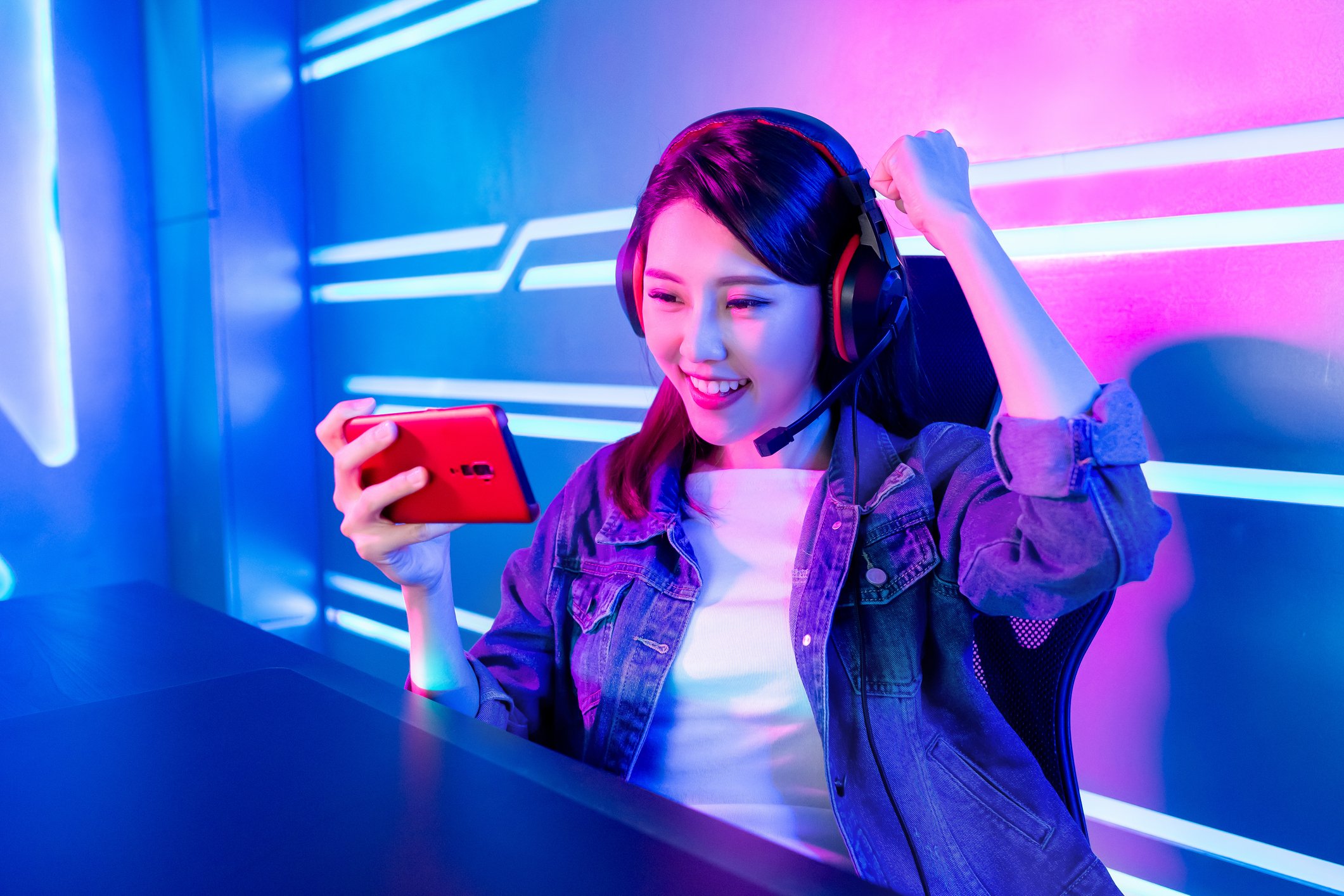 Young woman watching something on her smartphone and raising a fist in the air