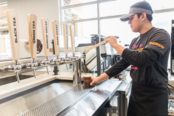 A Dunkin' employee fills a coffee cup.