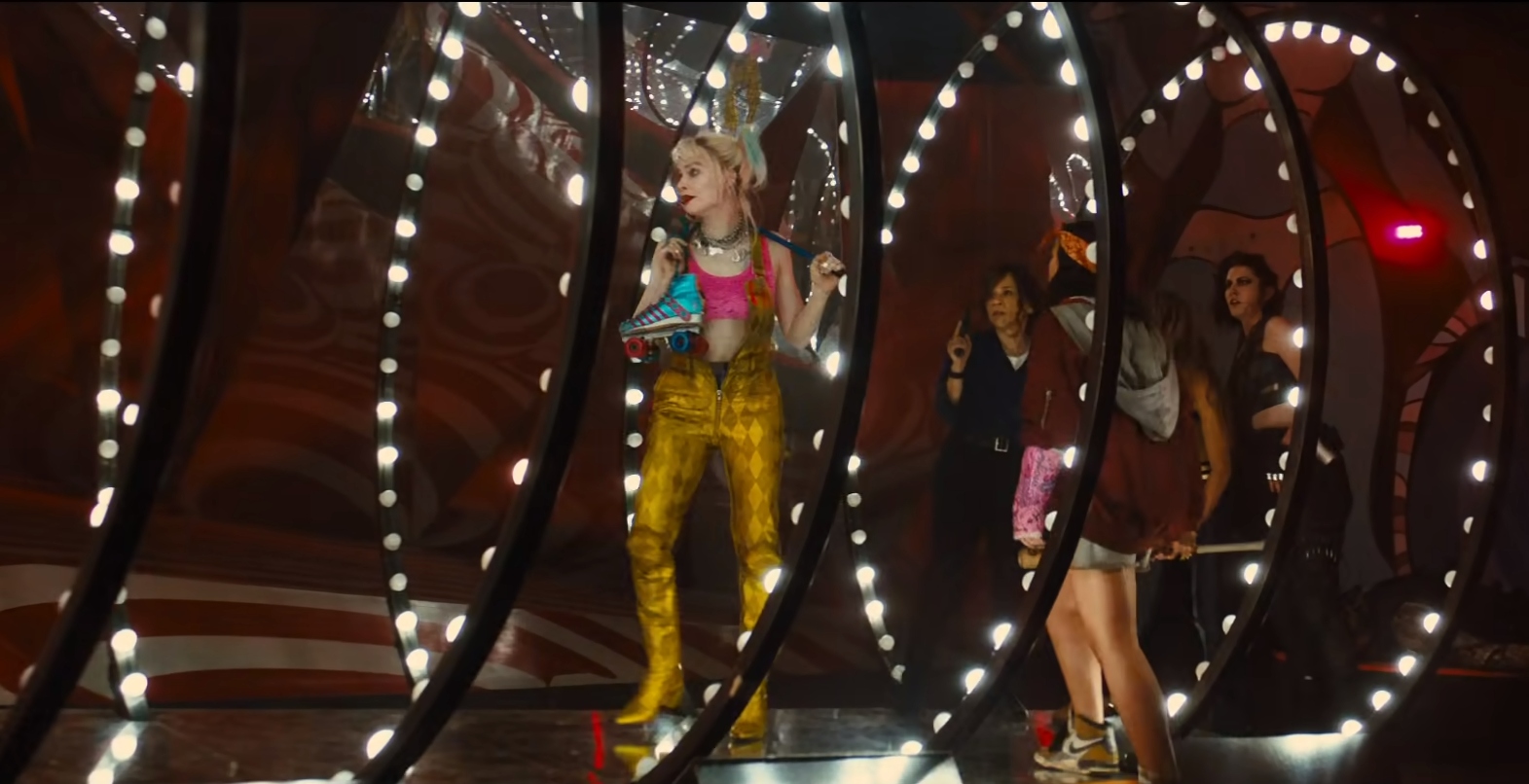 The Birds of Prey team walk down a brightly lit tunnel, led by Margot Robbie as Harley Quinn, in a stillframe from Harley Quinn: Birds of Prey.