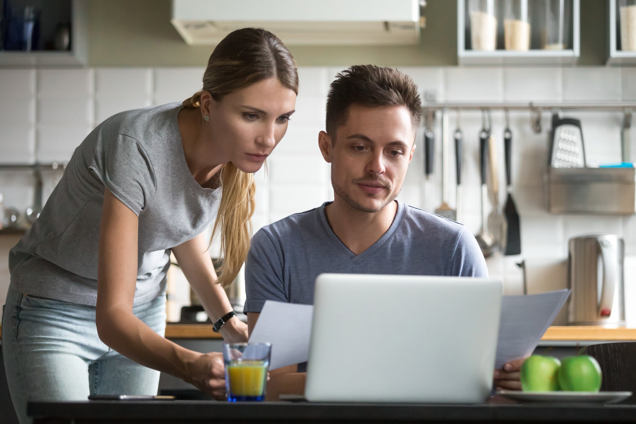Man sitting at laptop while woman stands next to him