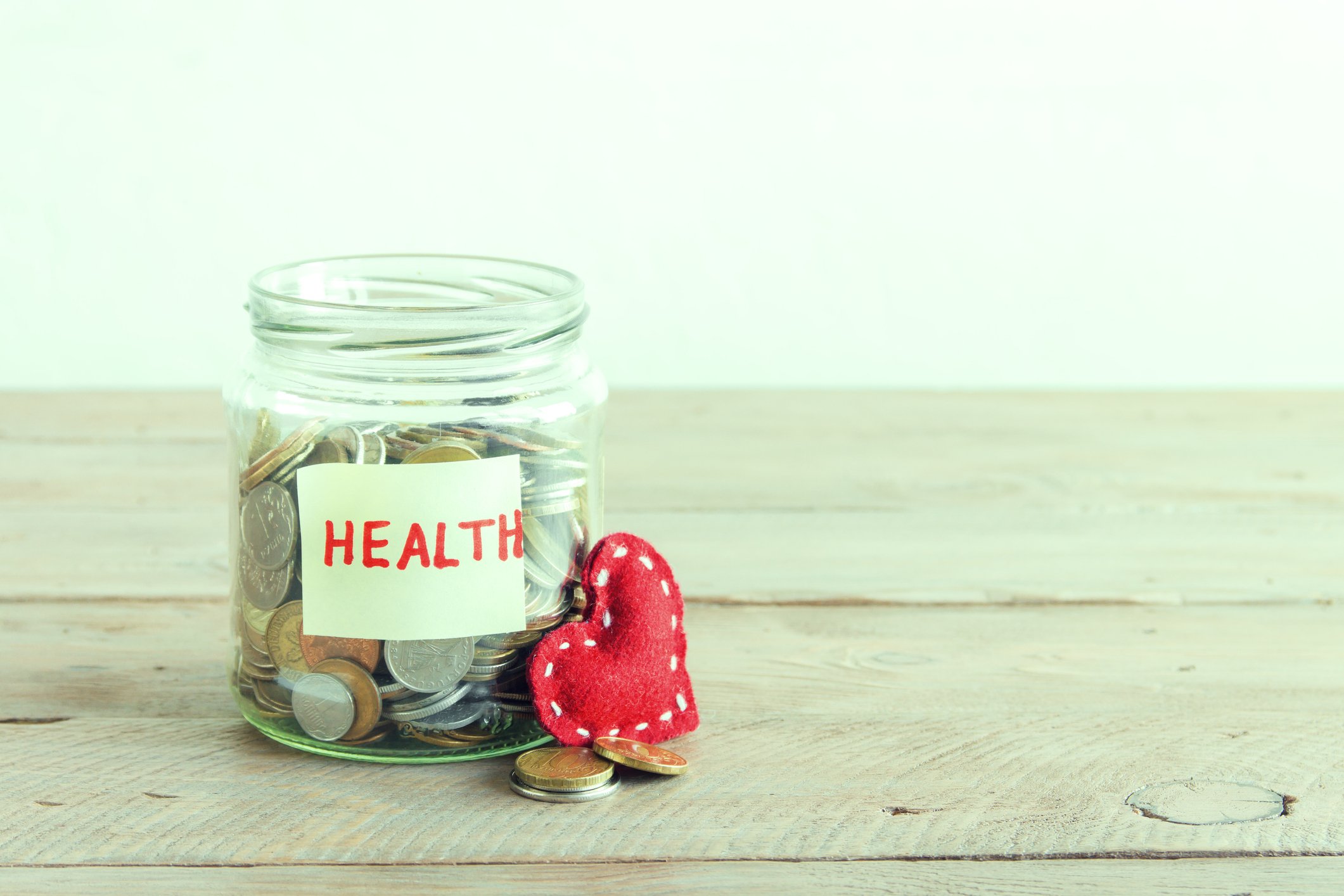Glass jar filled with coins labeled health with a felt heart next to it