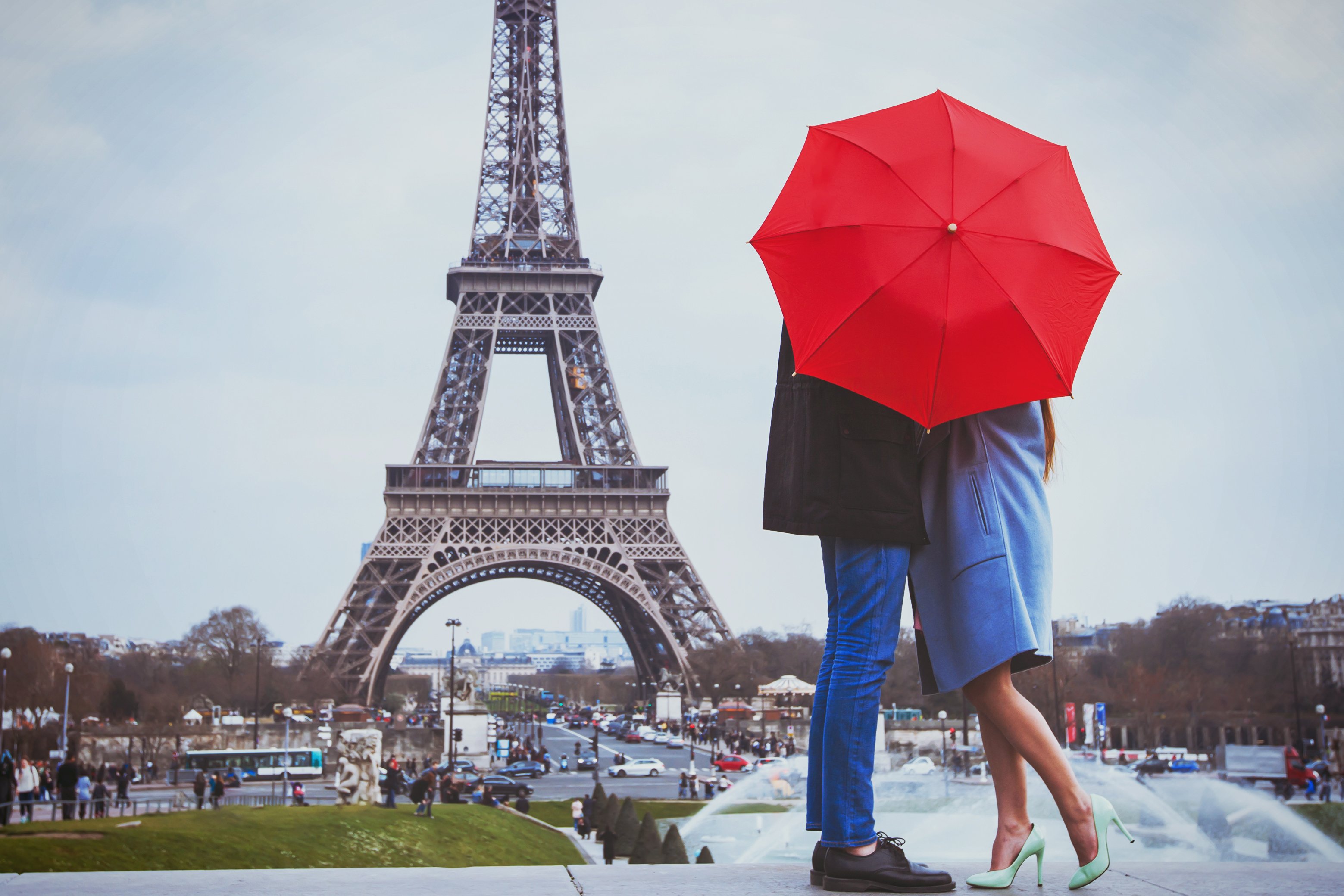 A couple kiss behind an umbrella at the Eiffel Tower