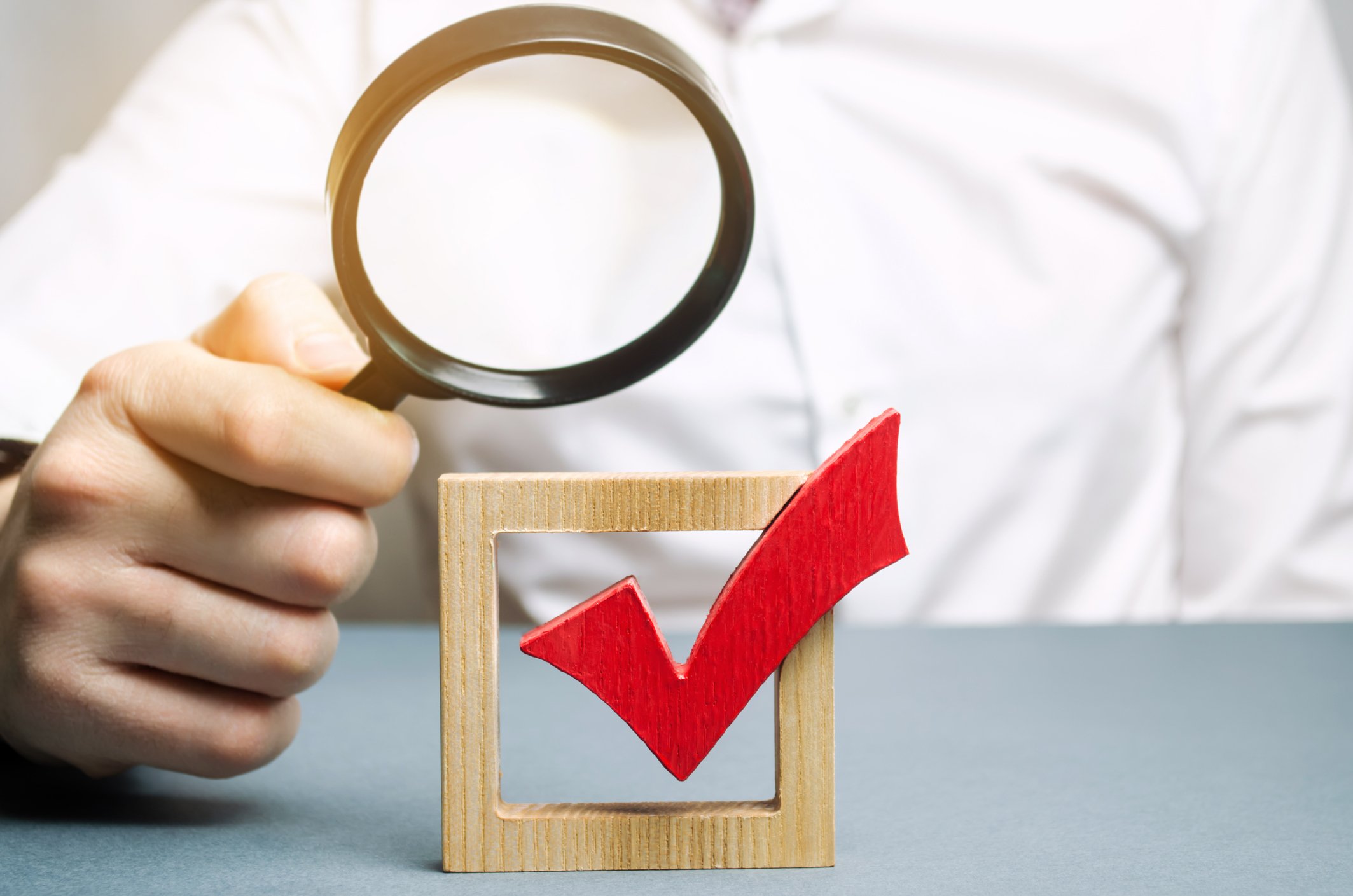 man magnifying glass red check mark