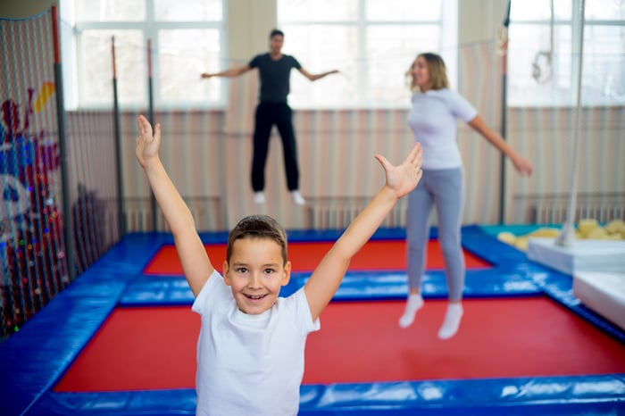 Kid in foreground jumping on a trampoline