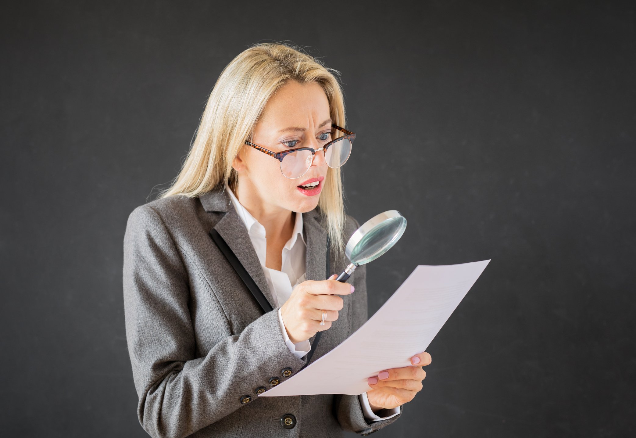 A woman looking at a piece of paper through a magnifying glass.
