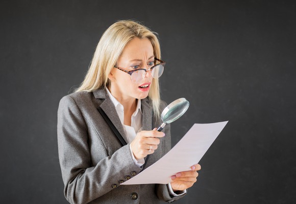 A woman looking at a piece of paper through a magnifying glass.