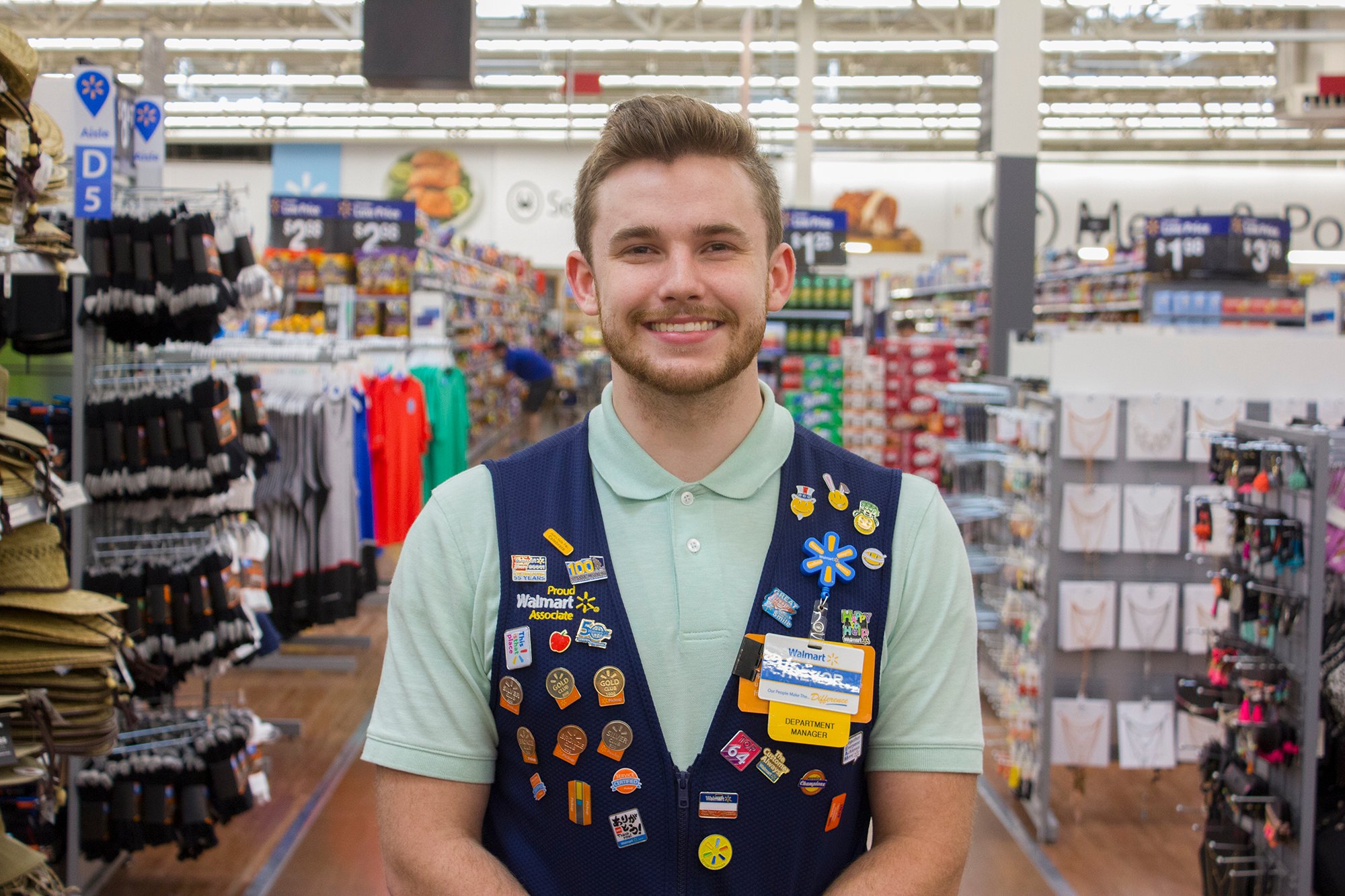 A Walmart sales associate standing in the store smiling.