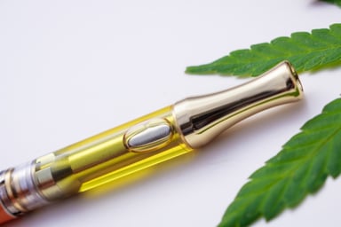 Vape pen and marijuana leaves close up