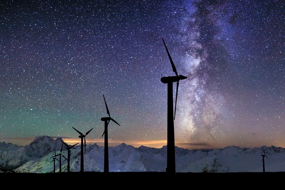 Silhouettes of wind turbines in front of a starry background.