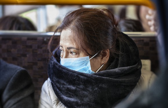 Asian woman wearing surgical mask on a bus