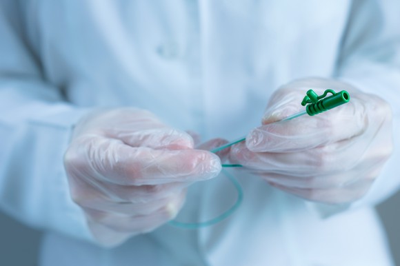 A medical professional holding a catheter.