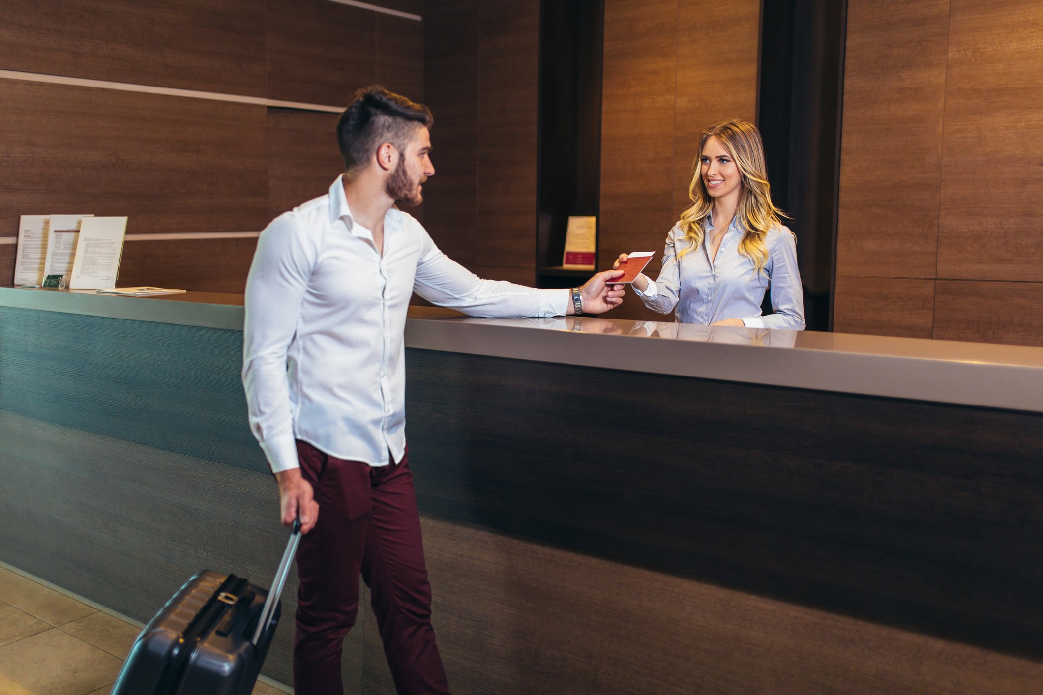 A young man checks into a modern hotel in the lobby.