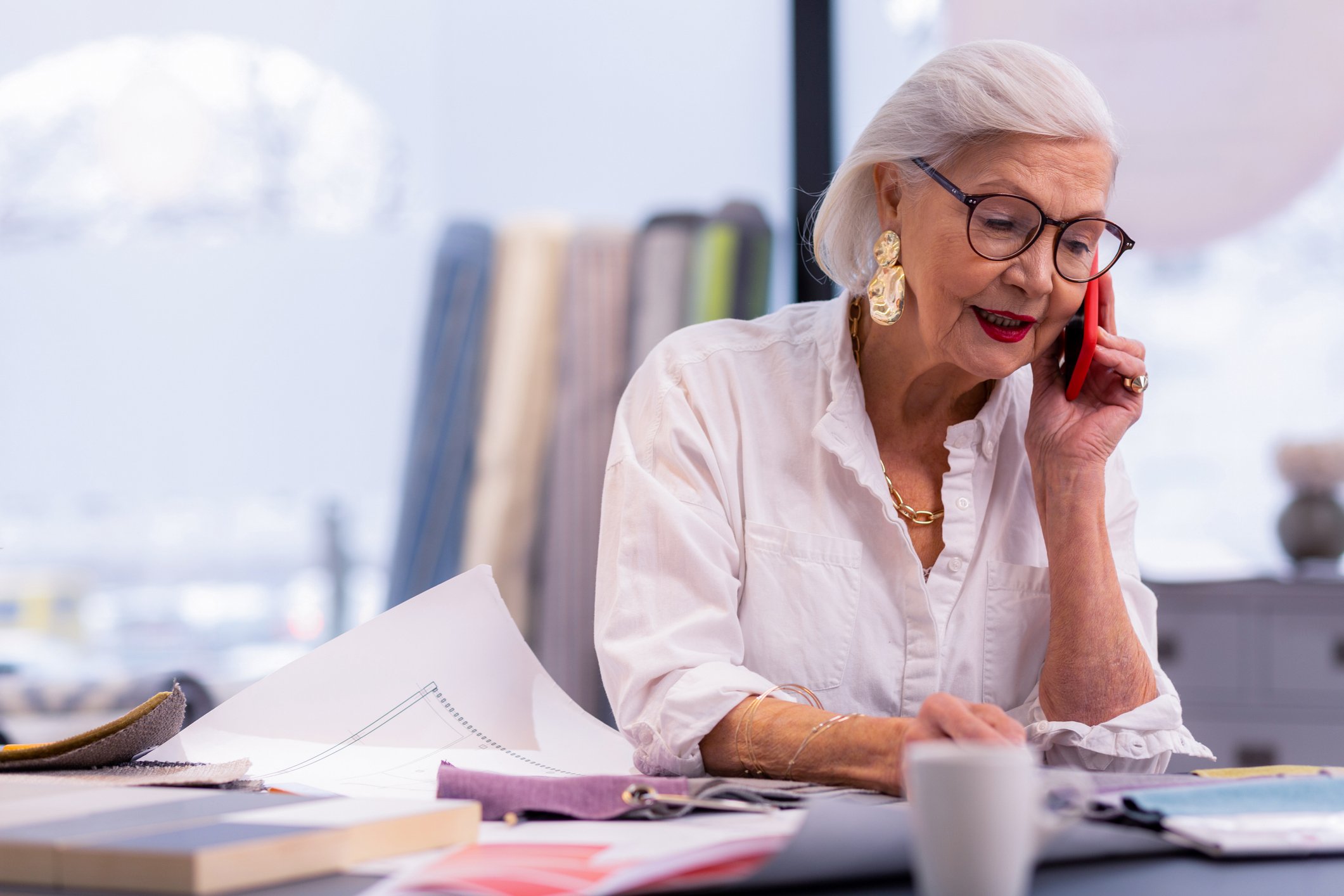 An older woman working at her desk and talking on the phone