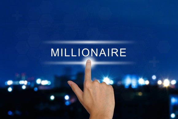 A finger is pointing to the word millionaire, against a blurry skyline at night.
