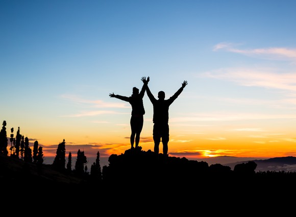 Couple celebrate reaching a mountain summit.