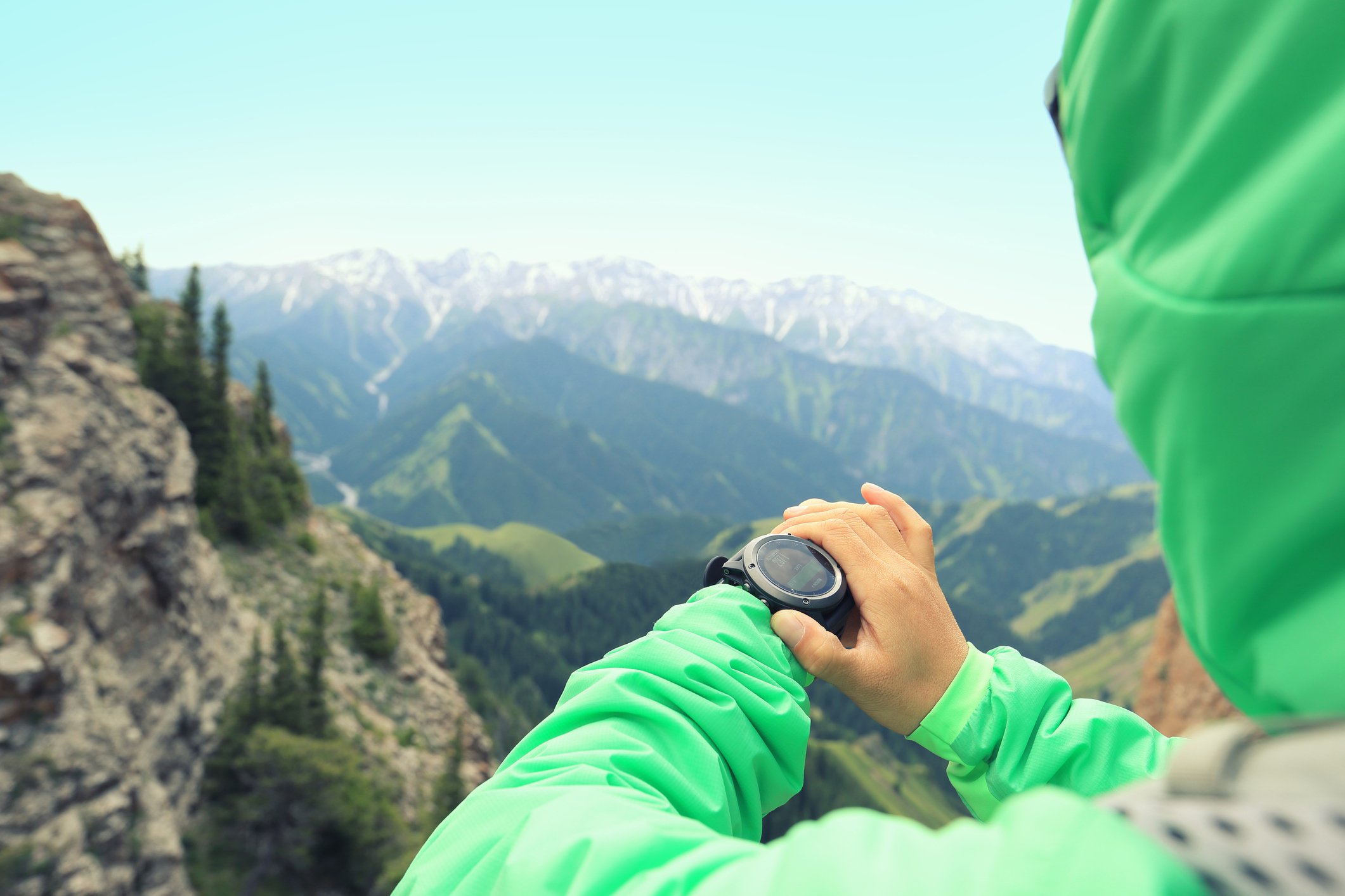 A hiker checks her smartwatch at the top of a peak