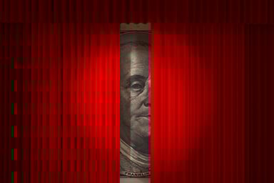 $100 bill behind red curtains