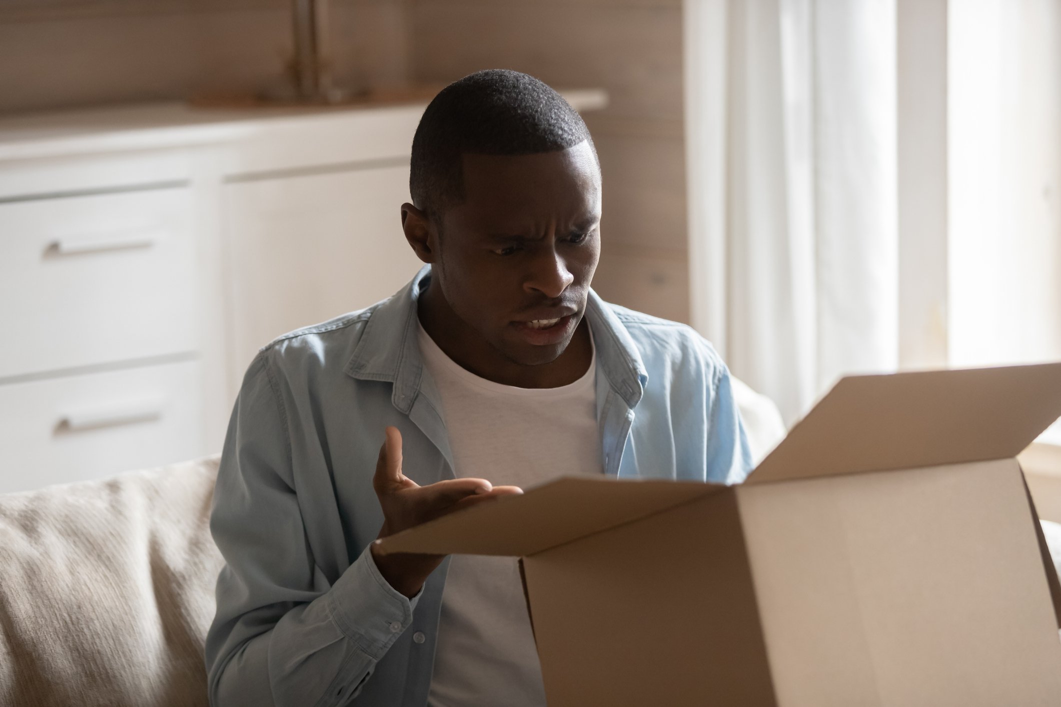 Man staring into open box, looking exasperated
