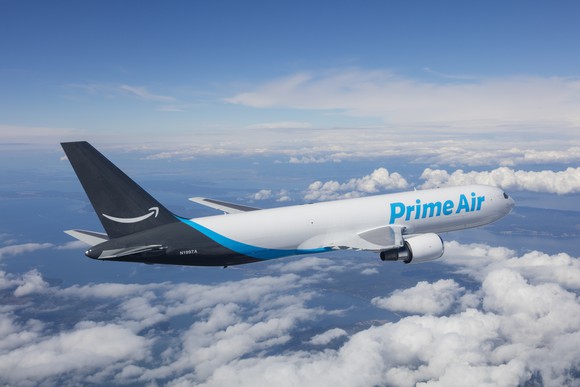 An airplane for Amazon Prime Air flies above a cloudy blue sky.