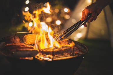 Meat being barbecued at night on an outdoor grill
