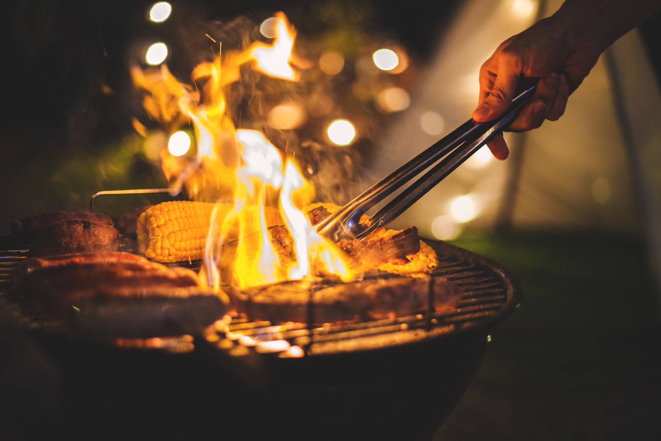 Meat being barbecued at night on an outdoor grill.