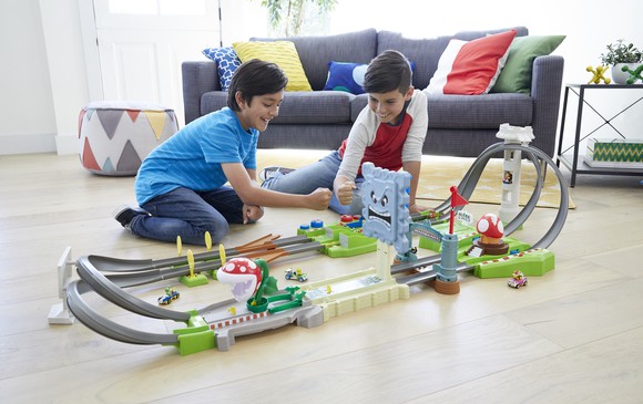 Two boys playing with a track set.