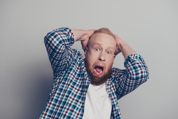 A man holding his head with a scared expression.
