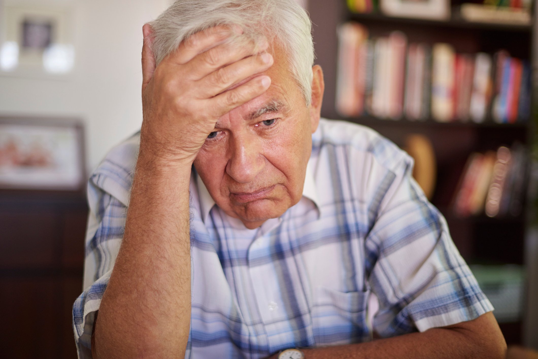 Older man with sad expression holding his head
