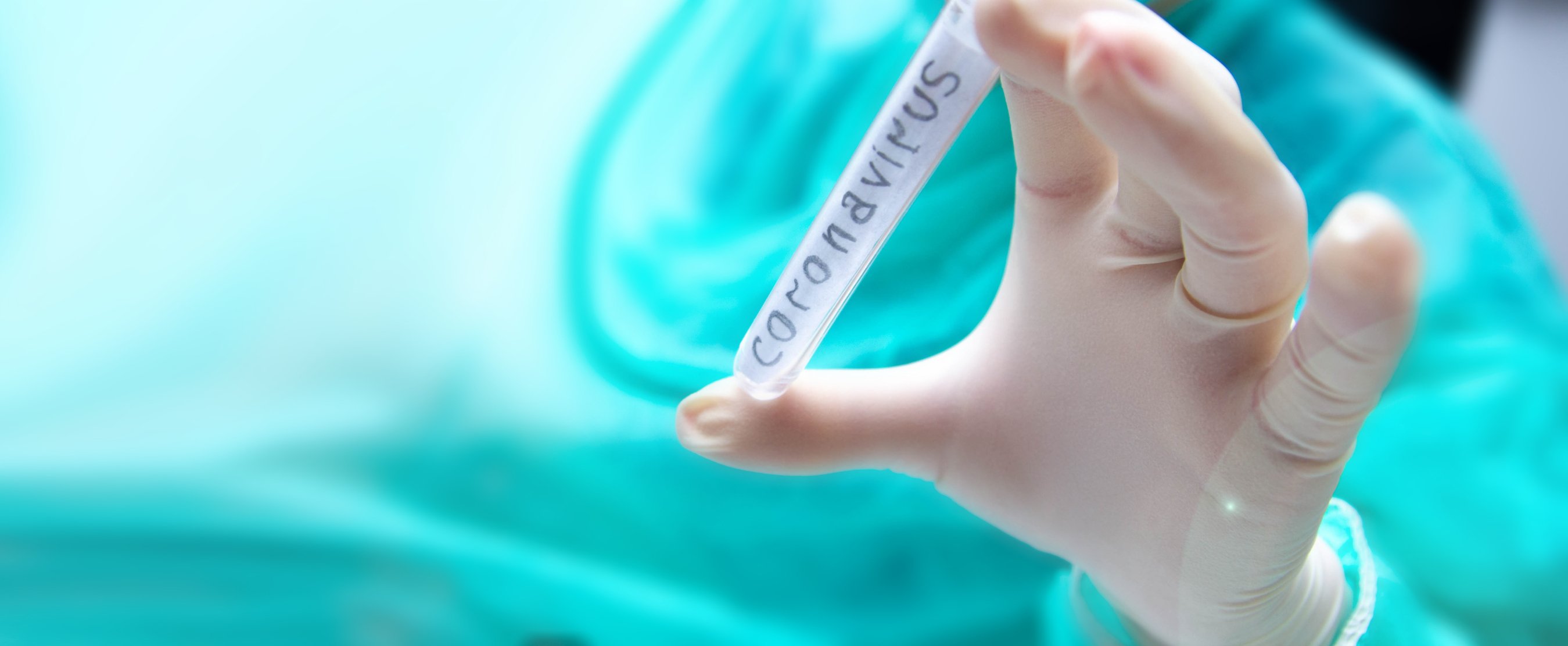 A gloved hand holds a plastic tube labeled coronavirus.
